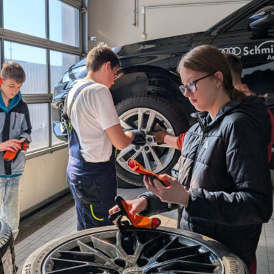 Auf dem Bild sind 3 Schüler*innen sowie ein Auzibi in der Audi Werkstatt zu sehen, wie sie dabei sind Radschraueben festzuziehen im Rahmen des Girls und Boys Day 2026